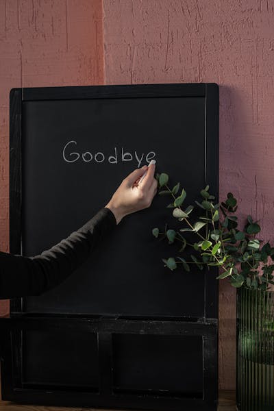 Eine Hand die goodbye auf eine Tafel schreibt