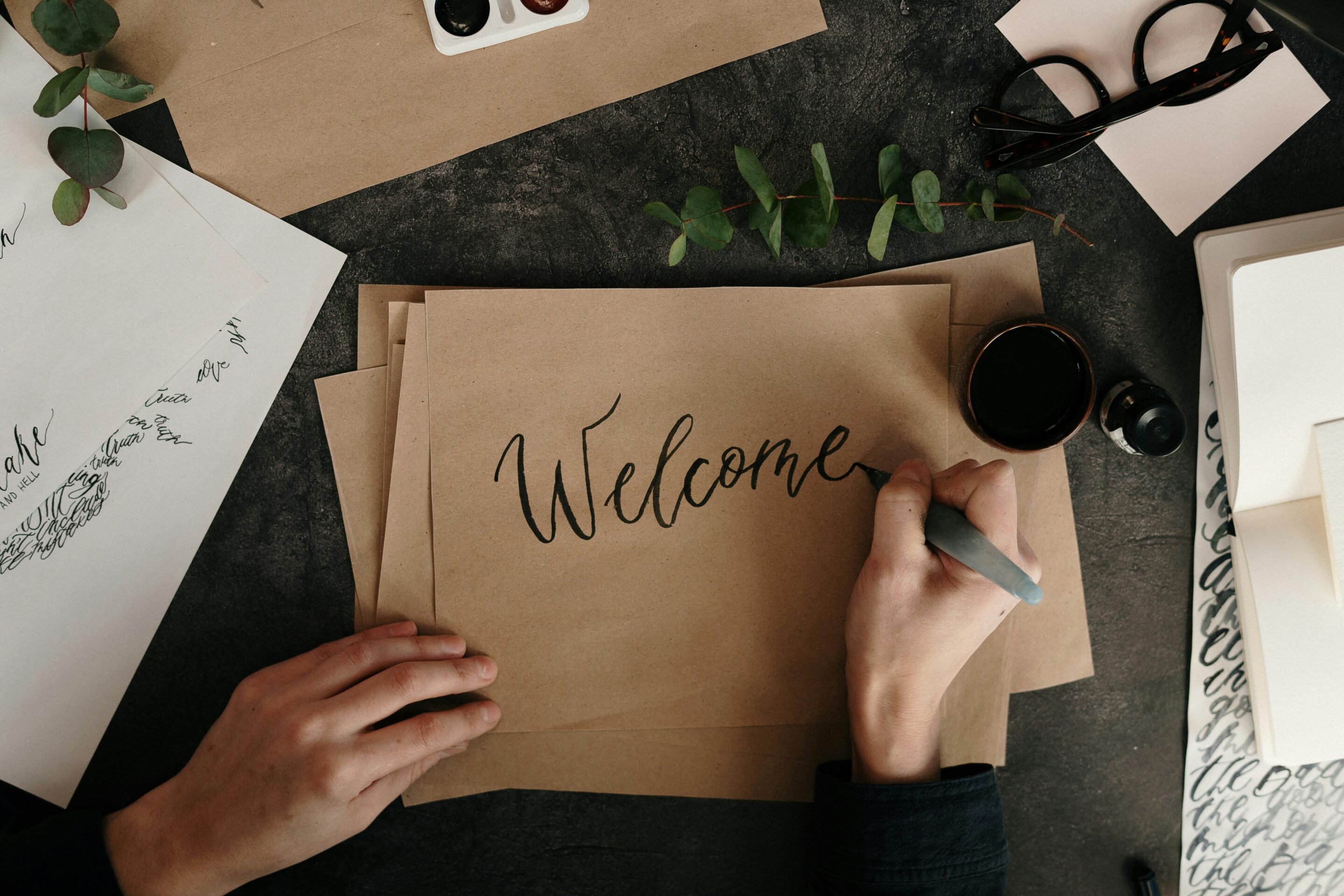 Eine Hand die Welcome auf ein Papier schreibt